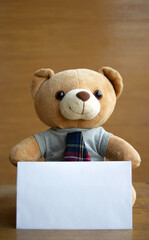 Portrait portrait brown teddy bears and white blank paper on brown wooden background. Birthday or anniversary card concept.