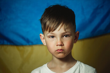 portrait of a crying boy on the background of the flag of Ukraine