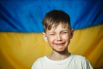 crying little boy on the background of the flag of Ukraine