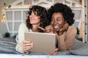 Happy gay couple looking at digital tablet together at home