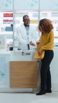 Vertical Video. Pharmacy Drugstore Checkout Counter: Professional Black Male Pharmacist Provides Service, Sells Medicine to Diverse Group Customers, they Pay Using Contactless Payment Credit Cards