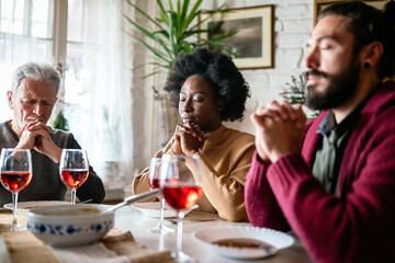 Family and religious concept. Group of multiethnic people with food praying before meal