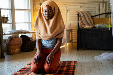 Young muslim black woman praying at home