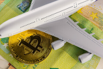 airplane and bitcoin stand on euro banknotes close-up