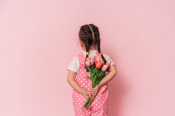 Little girl with bouquet of flowers against pink background. happy mother's day