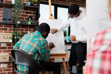 African american teacher helping student with drawing project during art class in creativity studio. Diverse students sketching vase model using grahpic pencil earning skill for personal personal