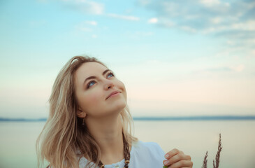 Portrait of young european woman looking up at the blue sky. Nude make-up. Beautiful girl portrait. Side view. Profile. Dream. Nature background. International woman day. Elegant style. Relaxation