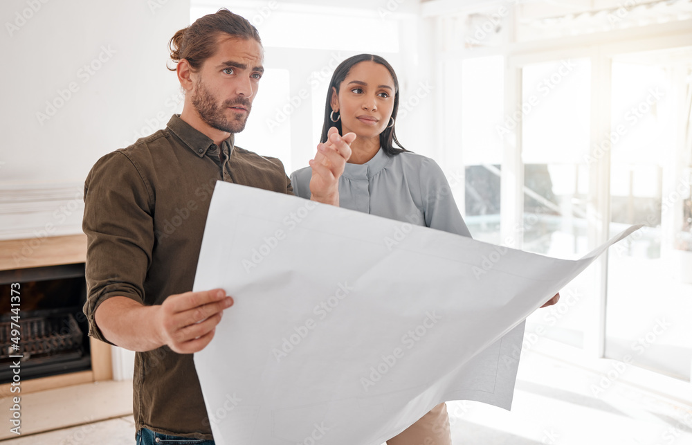 Poster making dreams a reality. shot of two young architects looking at building plans on site.