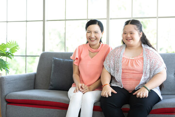 down syndrome teenage girl with mother looking something on sofa
