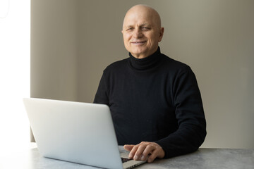 Portrait of senior man at home working on laptop