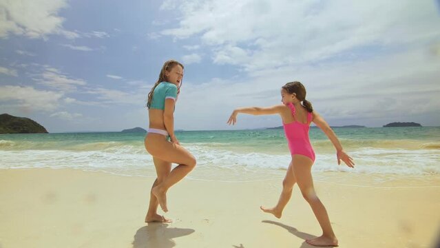 The happy fun woman with her child enjoying her outdoor vacation on tropical island. The optimistic funny mother with daughter dancing on shallow ocean. Concept summer holidays, dance beach party
