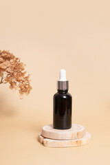 Wooden podium or pedestal with a dropper bottle of cosmetics oil or serum. Neutral beige monochrome skin care concept