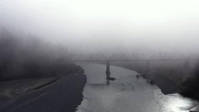 Train trestle over Eel River in California, foggy landscape, drone forward.