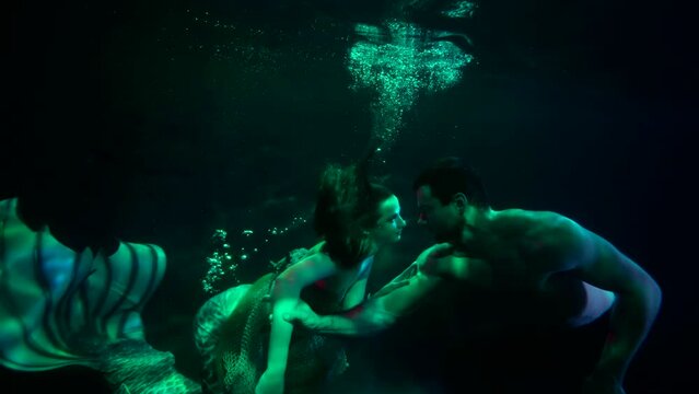 mysterious love story of mermaid and brawny man, underwater shot of swimming lovers