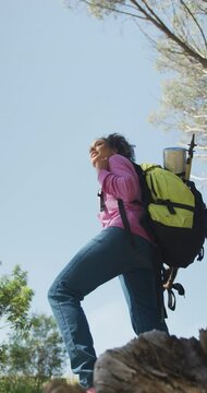 Vertical video of happy african american woman with backpack hiking in countryside, enjoying view