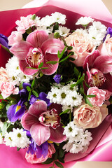 Mother's day, womens day or birthday card. Beautiful bouquet of blooming orchids, carnations and irises on a light pink background.
