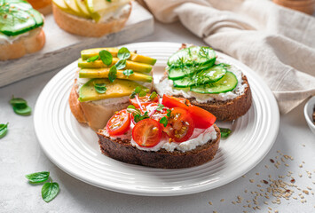 Crostini on rye and wheat bread with feta, vegetables, fruits and fresh herbs.