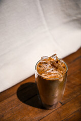 Ice coffee on a table with cream being poured into it showing the texture and refreshing look of the drink