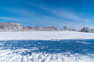Germany, White snow covered winter wonderland scene landscape on sunny day with blue sky and many footsteps of tourists walking through the snow