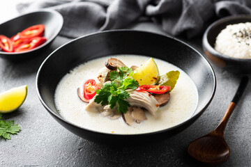 Tom Kha Gai, Thai soup in a black bowl on a concrete background, selective focus