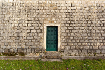 Old stone wall with door. Village church.