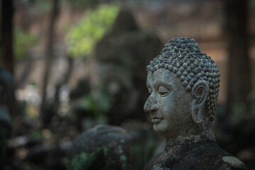 Ancient old ruin Head of Buddha statue carved from sandstone was destroyed and abandoned left in the Wat U Mong Temple.