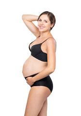 Fototapeta premium Young pregnant woman in black swimsuit. Girl expecting a baby and touching her belly isolated on white background.