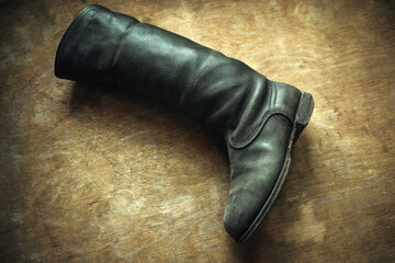 An old leather boot on a wooden background in retro style.Repair of old shoes. Shoes of the last century.