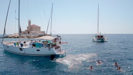 Young friends jumping from sailboat. Yachting. Sail boat party day. Summer luxury boat trip vacation