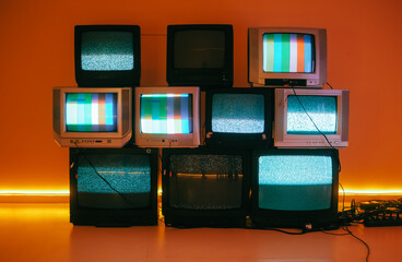 Old vintage tvs on a floor in a room with colored neon light. - obrazy, fototapety, plakaty