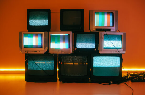 Fototapeta Old vintage tvs on a floor in a room with colored neon light.