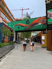 Two people walking in a city with modern buildings and a construction crane. Taken in Munich Germany.