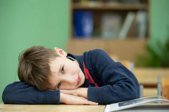Tired little boy put his head on the school desk. Child at school.