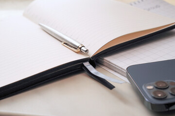 Communication technologies. On the table is a mobile phone, a diary, a pen.