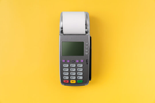 Card reader machine with invoice bill on yellow background. Online payment concept.