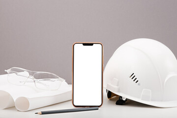 white helmet, smartphone, gloves, plan, drawings, construction glasses on gray background,...