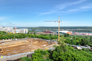 construction of new structure at stage of excavation and driving piles, tower crane stands against...