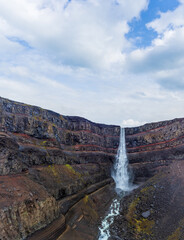 Hengifoss waterfall with red layers under cloudy sky
