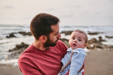 Young single father hugging his baby son on the beach