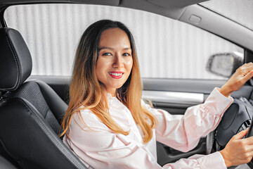 Asian girl is driving a car. Buying a new car and driving pleasure. Beautiful woman driver.