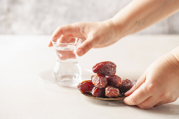 Glass of water and dry dates on saucer ready to eat for iftar time. Islamic religion and ramadan concept.