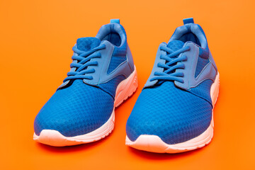 pair of comfortable blue sport shoes on orange background, jogging shoes
