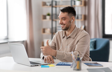 distance education, school and remote job concept - happy smiling male teacher or student with laptop computer and earphones having online class or video call at home office