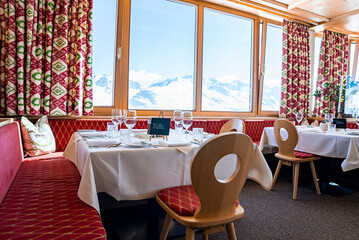 Elegant table setting beside window in hotel against snowcapped mountains