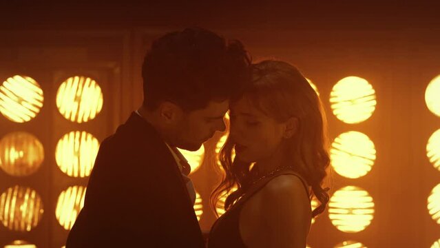 Sensual couple dancing intimately at club lights. Young man caressing hot girl.