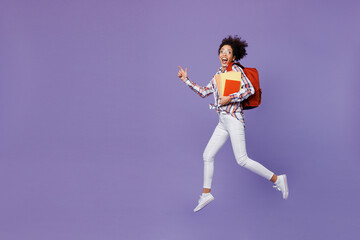 Full body excited happy young girl woman of African American ethnicity teen student in shirt hold backpack jump high hurry up run fast isolated on plain purple background Education in college concept
