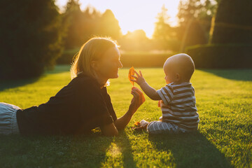 Young mother and baby playing in park at summer. Beautiful mom and child outdoors. Parent with kid spend time together. Happy healthy family at sunlight. Eco sustainable lifestyle. Positive emotions.