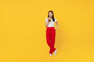Fototapeta na wymiar Full size body length young girl woman of Asian ethnicity 20s years old in casual clothes hold takeaway delivery craft paper brown cup coffee to go isolated on plain yellow background studio portrait.