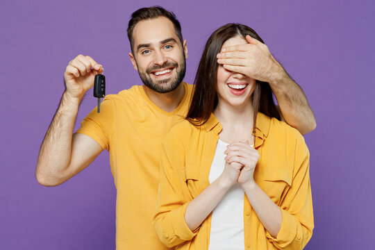 Young Smiling Surprised Happy Fun Couple Two Friends Family Man Woman Together Wear Yellow Clothes Cover Eyes Hold Car Key Fob Keyless System Gift Isolated On Plain Violet Background Studio Portrait.