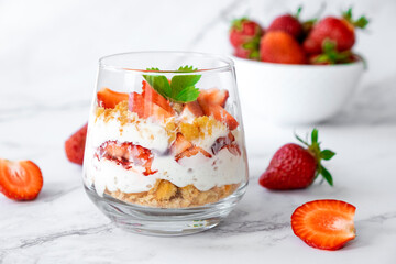 Berry dessert in glass with fresh strawberry, biscuit and whipped cream. Vegan lactose free dessert with alternative milk of coconut. Recipe of healthy organic dessert, cheesecake or berry trifle cake